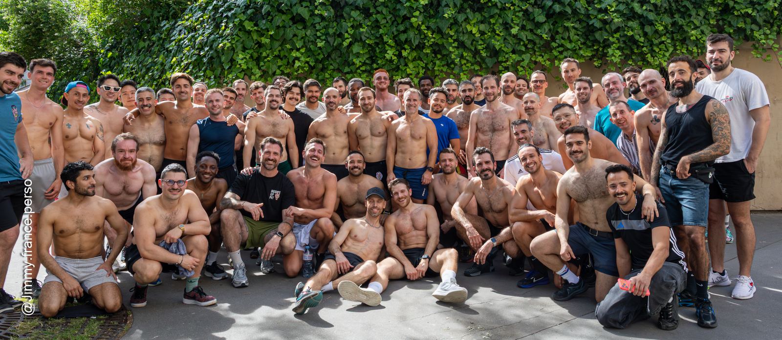 Photo de groupe de la communauté House Of Fit, une soixantaine de sportifs souriants réunis en extérieur devant un mur de lierre